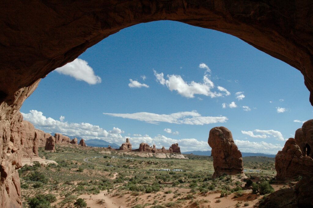 a view through a large rock archway with Arches National Park in the background